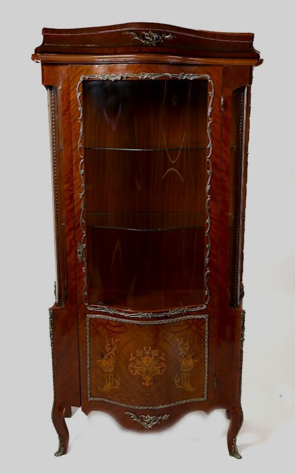 A corner cabinet with an intricate design on the front.