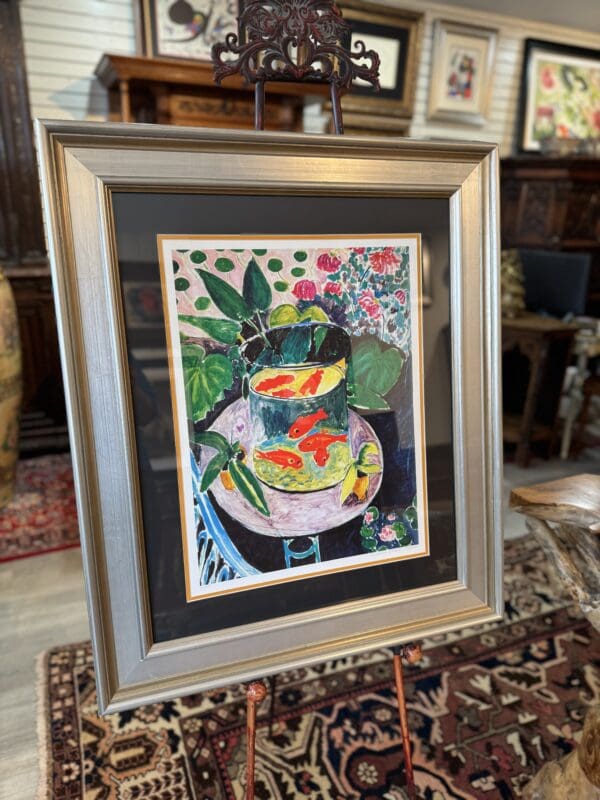 Framed painting of fish in a bowl with flowers.