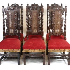 Four ornate wooden chairs with red upholstery.