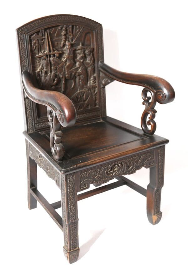 Ornate carved wooden armchair with figures.