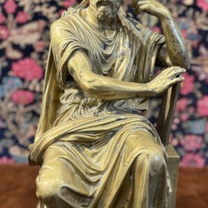 Seated statue on patterned background.