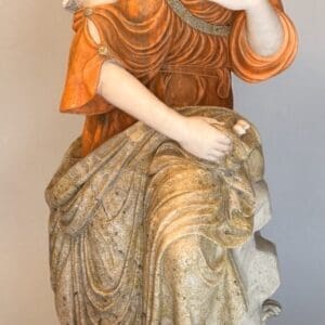 Marble statue of seated woman with flowers.