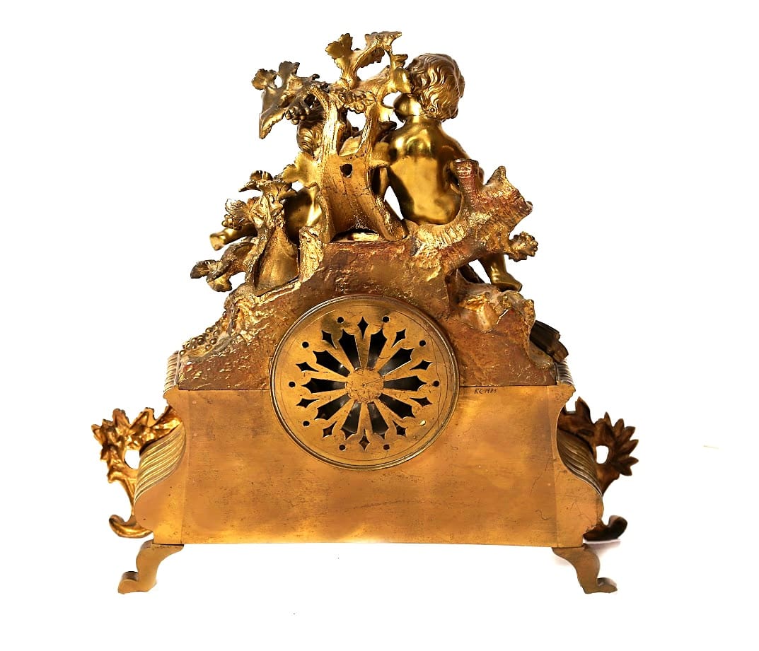 Back view of French Rococo-style mantel clock showing pierced brass movement cover and sculpted case