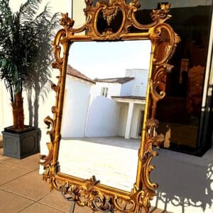 Beautiful 57 inch Italian giltwood mirror with hand-carved Rococo scrollwork and pierced acanthus crest at The Chapman Collection