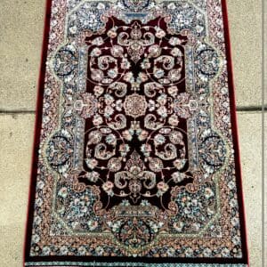 New Persian hand-finished Silk Qum carpet, 4' x 2'7", with a rich ruby-red field and intricate blue, ivory and rose detailing at The Chapman Collection