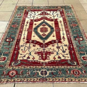 Handmade Indian Geometric Carpet with ivory ground, muted teal-green border and burgundy geometric medallion, 10 feet 2 inches by 7 feet 1 inch